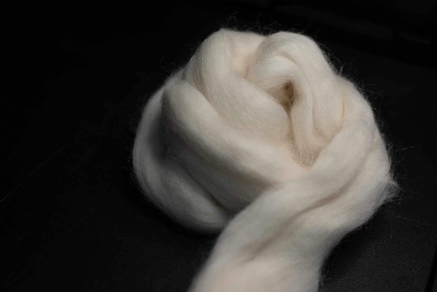 Alpaca wool roving (combed top) rolled into a loose ball.